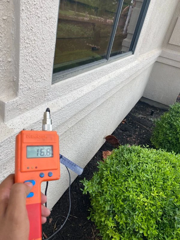 Handheld moisture meter used at a stucco test location below a window