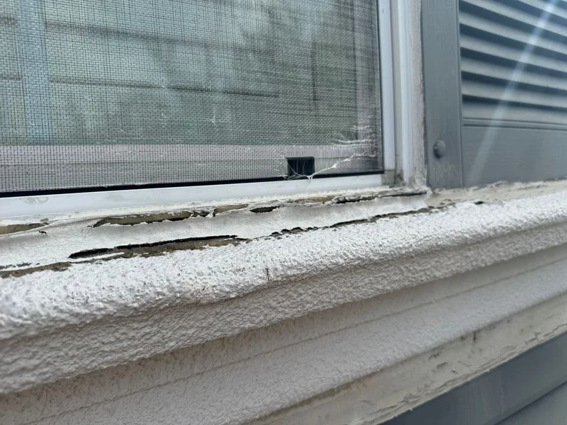 Deteriorated and separating material along the lower edge of a stucco window sill